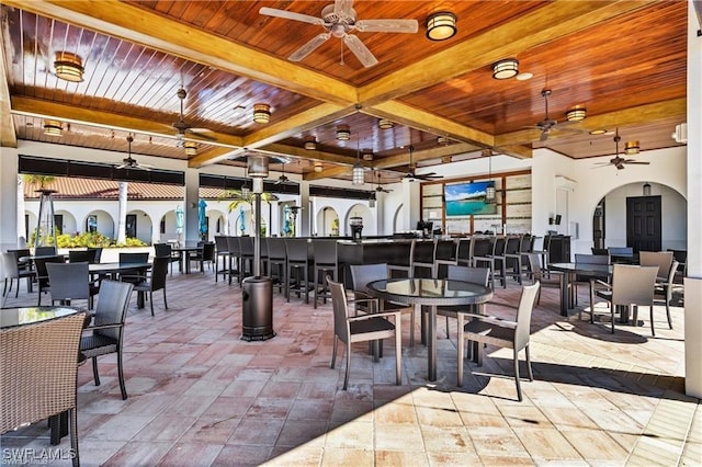 dining room featuring a wealth of natural light, arched walkways, wooden ceiling, and beamed ceiling