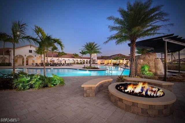 pool at dusk with a patio area and an outdoor fire pit