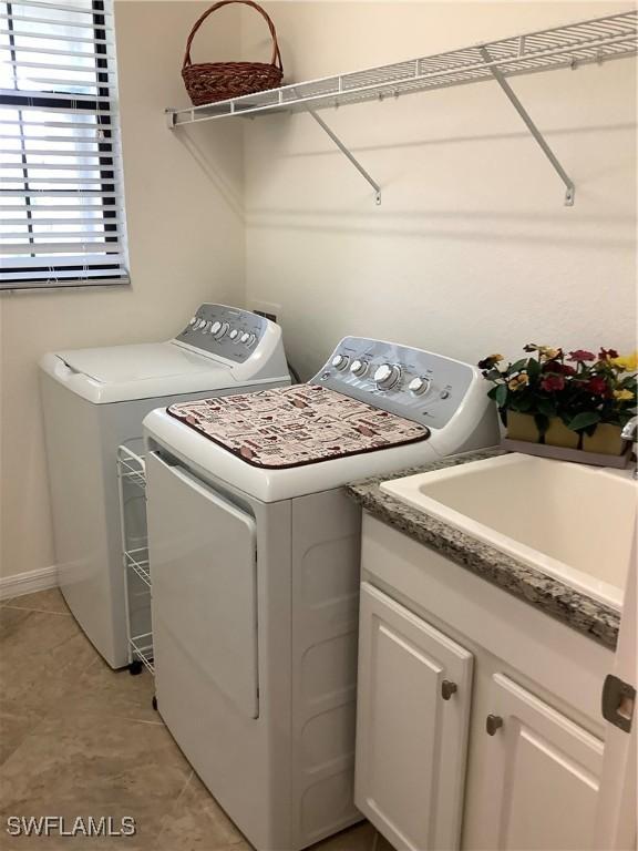 clothes washing area with washing machine and dryer, sink, and light tile patterned floors