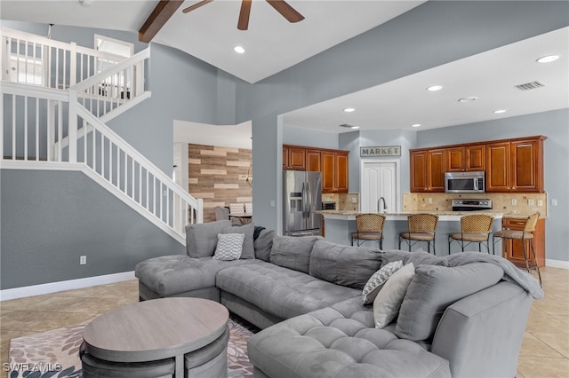 living room featuring sink, ceiling fan, light tile patterned floors, and vaulted ceiling with beams