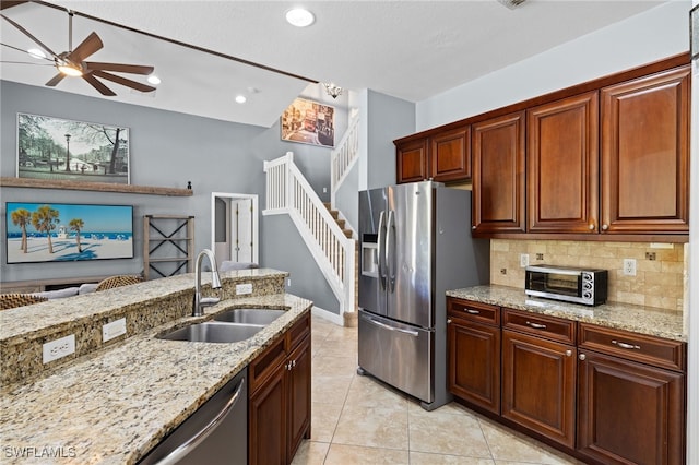 kitchen with stainless steel appliances, sink, light stone counters, and light tile patterned floors