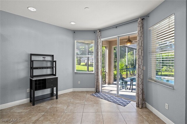 doorway with light tile patterned flooring and ceiling fan