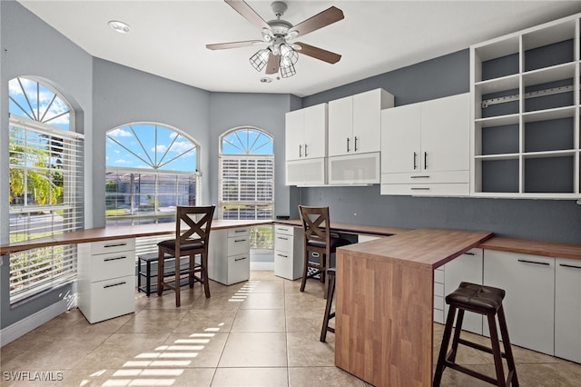 interior space with a breakfast bar, white cabinets, a healthy amount of sunlight, and butcher block countertops