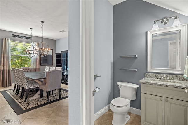 bathroom with an inviting chandelier, vanity, toilet, and tile patterned flooring