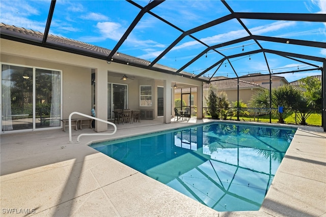 view of pool with a patio, glass enclosure, and ceiling fan