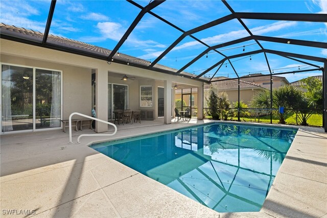 view of swimming pool with a patio, ceiling fan, and glass enclosure