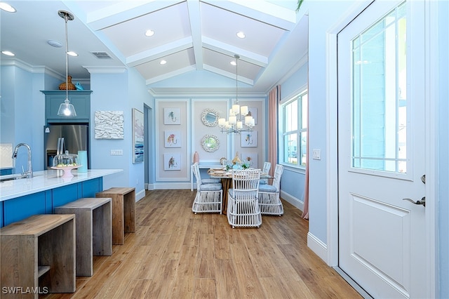 dining room with sink, lofted ceiling with beams, crown molding, a notable chandelier, and light hardwood / wood-style flooring