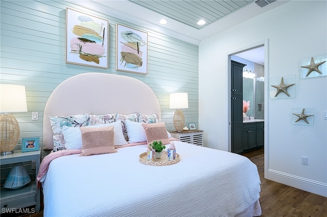 bedroom featuring ensuite bathroom and dark hardwood / wood-style floors