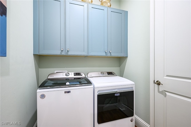 washroom with independent washer and dryer and cabinets