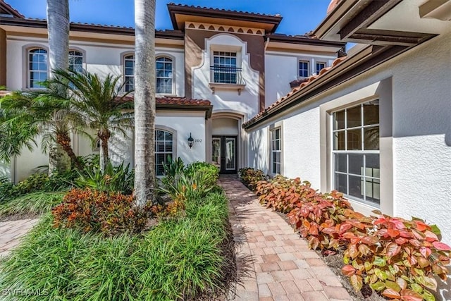 doorway to property with stucco siding, a tile roof, and french doors