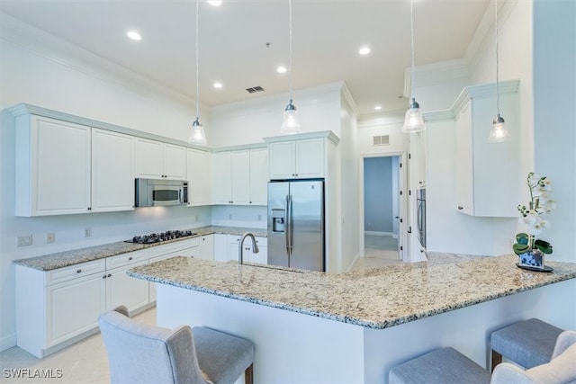 kitchen featuring appliances with stainless steel finishes, a breakfast bar area, kitchen peninsula, and decorative light fixtures