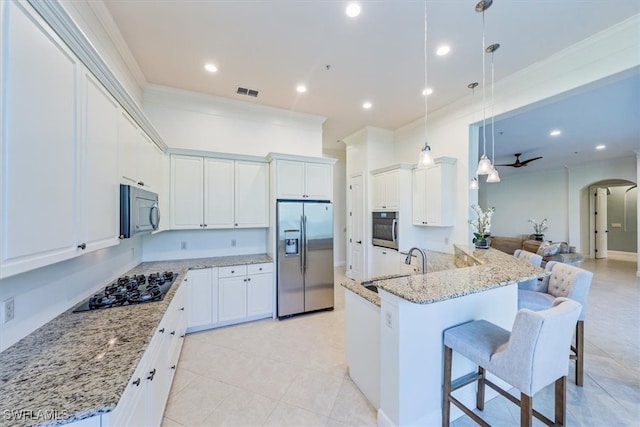 kitchen with hanging light fixtures, appliances with stainless steel finishes, white cabinetry, kitchen peninsula, and a breakfast bar area