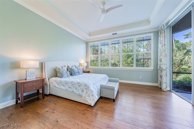 bedroom with ornamental molding, access to outside, wood-type flooring, ceiling fan, and a raised ceiling