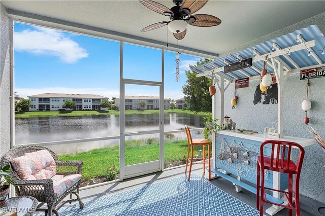 sunroom / solarium featuring a wealth of natural light, a water view, and ceiling fan