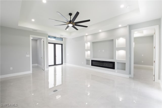 unfurnished living room with ceiling fan and a raised ceiling