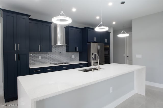 kitchen with wall chimney exhaust hood, stainless steel refrigerator with ice dispenser, pendant lighting, a large island with sink, and black electric stovetop