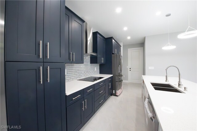 kitchen featuring pendant lighting, backsplash, stainless steel appliances, sink, and wall chimney range hood