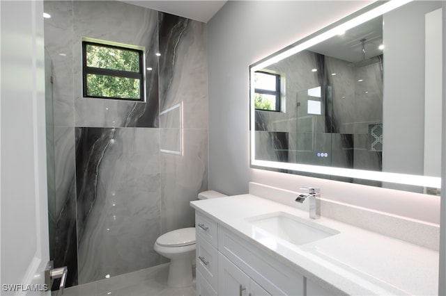 bathroom featuring vanity, toilet, and a tile shower