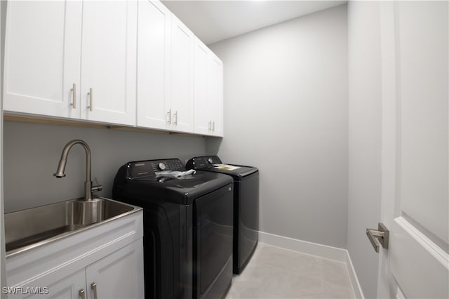 laundry room featuring light tile patterned floors, cabinets, washer and clothes dryer, and sink