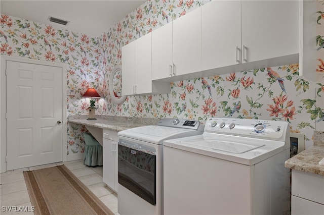 clothes washing area featuring cabinets, light tile patterned flooring, and washing machine and dryer