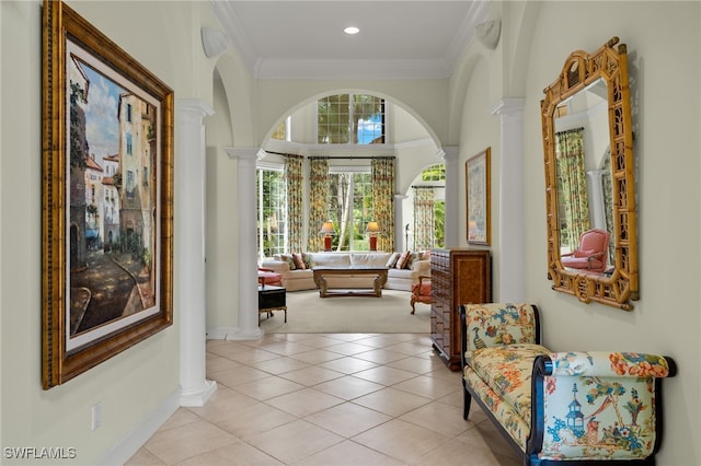 hallway with ornamental molding, light tile patterned flooring, and ornate columns