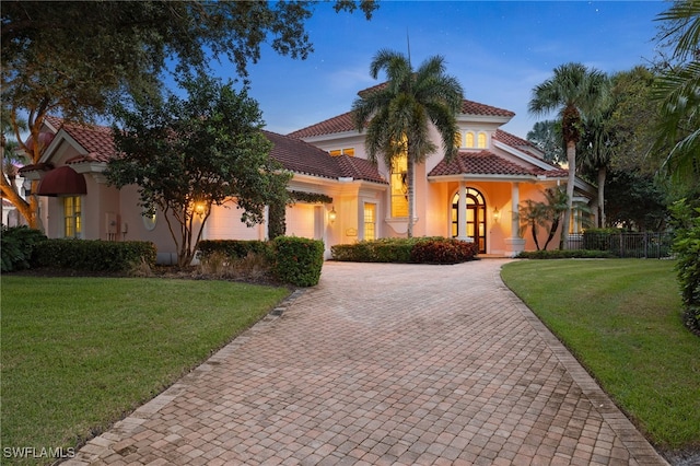 7005 Verde Way, Naples, FL 34108 - mediterranean / spanish-style home with a front lawn, a tile roof, stucco siding, and decorative driveway