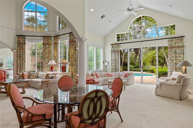 dining room with ornate columns, carpet, ceiling fan, and high vaulted ceiling