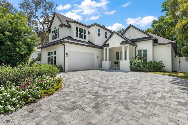 view of front of house with decorative driveway, fence, an attached garage, and stucco siding