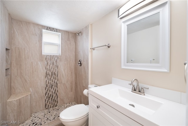 bathroom with vanity, toilet, and tiled shower