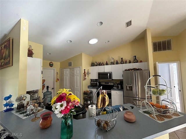 kitchen featuring white cabinets, stainless steel appliances, and vaulted ceiling