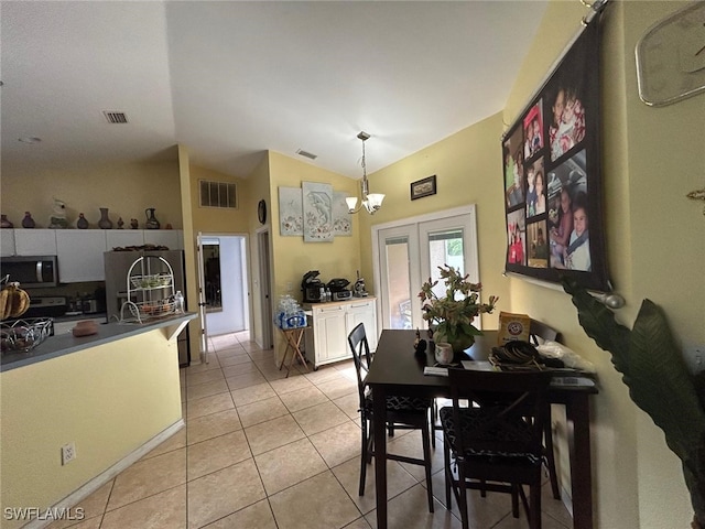 dining room featuring french doors, lofted ceiling, an inviting chandelier, and light tile patterned flooring