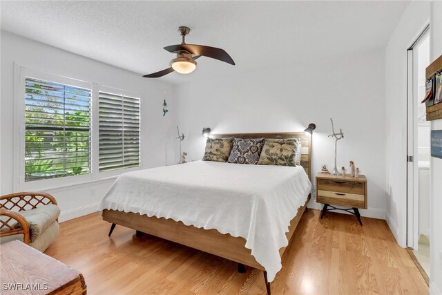 bedroom with a textured ceiling, ceiling fan, and light hardwood / wood-style floors