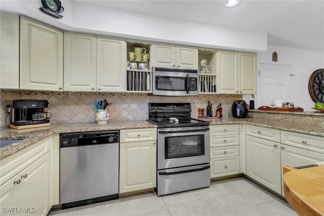 kitchen with light stone countertops, cream cabinets, appliances with stainless steel finishes, tasteful backsplash, and light tile patterned flooring