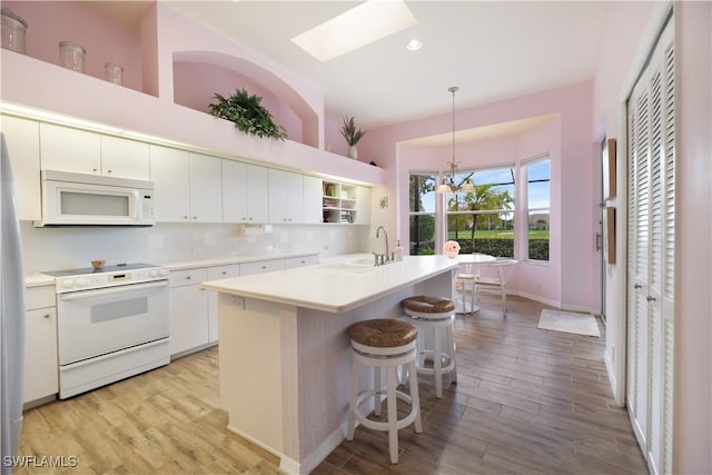 kitchen with light hardwood / wood-style flooring, white cabinets, pendant lighting, and white appliances