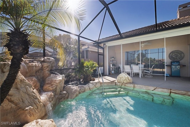 view of swimming pool with a lanai, ceiling fan, a patio area, and grilling area