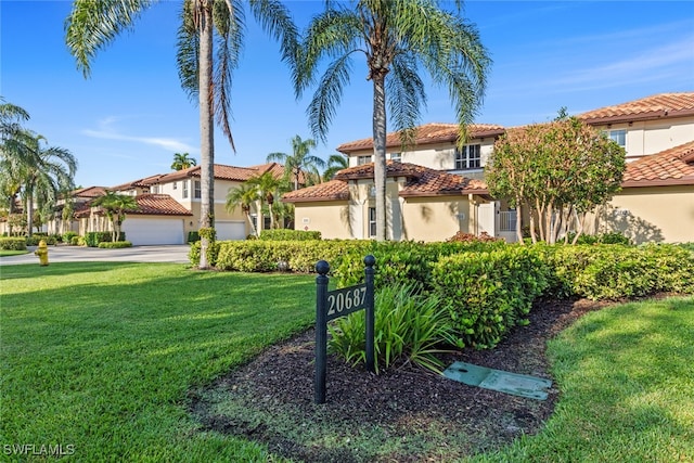 mediterranean / spanish home featuring a front lawn and a garage