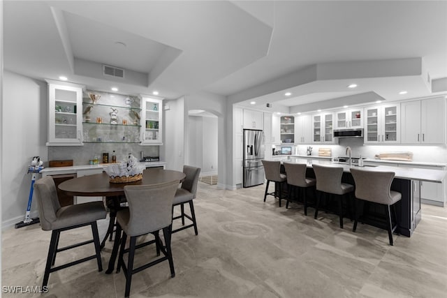 dining space featuring a raised ceiling and indoor bar