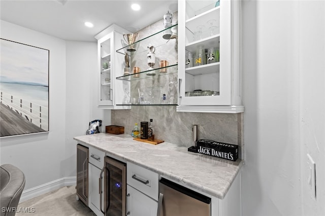 bar featuring decorative backsplash, light stone countertops, beverage cooler, and white cabinetry