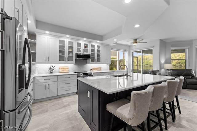 kitchen with a kitchen island with sink, stainless steel fridge, a wealth of natural light, and sink