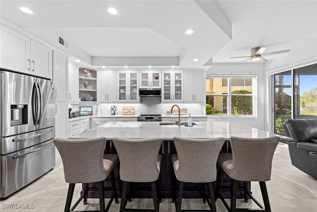 kitchen featuring stainless steel fridge, decorative backsplash, sink, and white cabinets