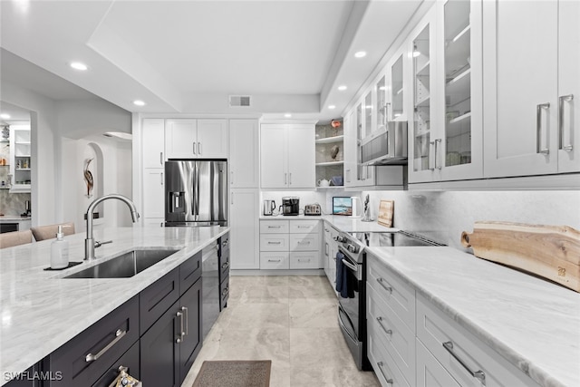 kitchen with sink, stainless steel appliances, light stone countertops, exhaust hood, and white cabinetry