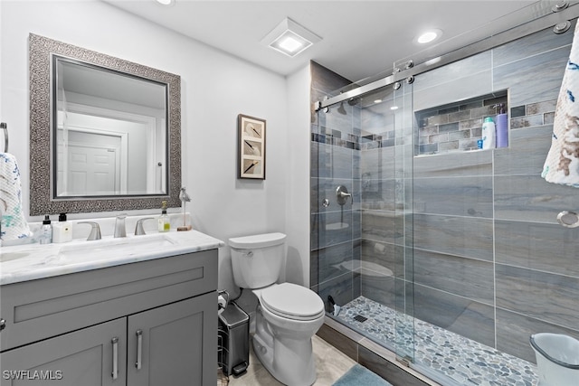 bathroom featuring vanity, toilet, and a shower with shower door