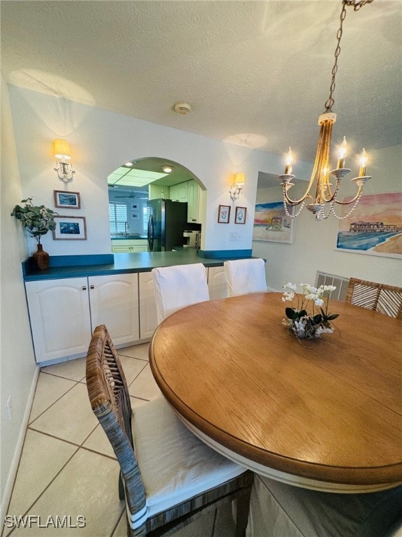 dining area featuring a chandelier, light tile patterned flooring, and a textured ceiling