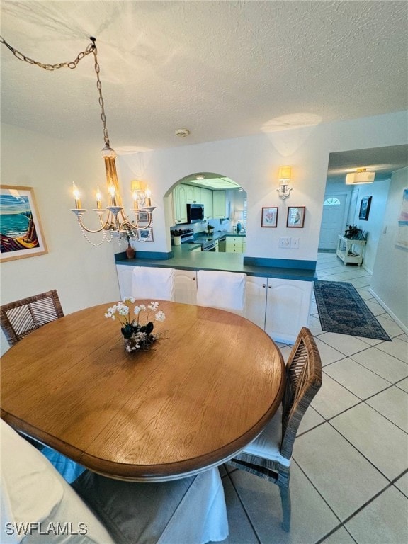 tiled dining area featuring a textured ceiling and a chandelier