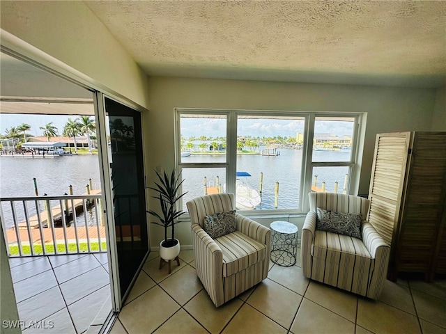 sitting room with a water view, a textured ceiling, and light tile patterned flooring