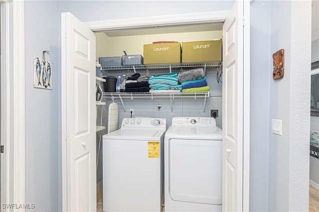 clothes washing area with washer and clothes dryer and light hardwood / wood-style floors