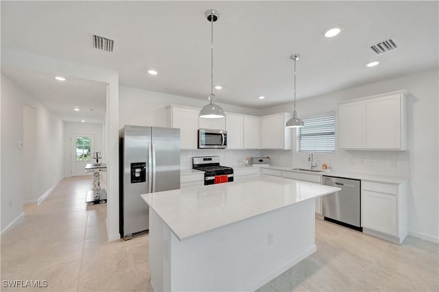 kitchen with white cabinets, appliances with stainless steel finishes, a kitchen island, sink, and hanging light fixtures