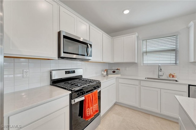 kitchen featuring tasteful backsplash, sink, white cabinetry, appliances with stainless steel finishes, and light tile patterned floors