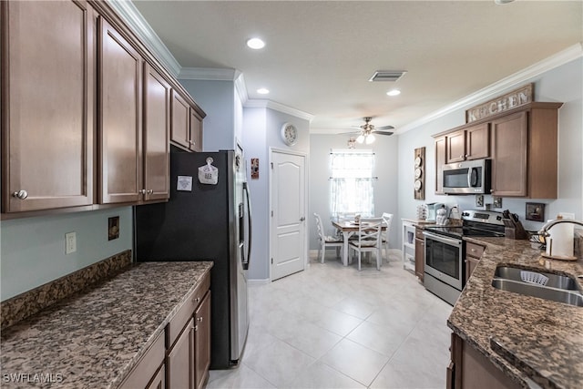 kitchen with stainless steel appliances, sink, dark stone counters, ceiling fan, and ornamental molding