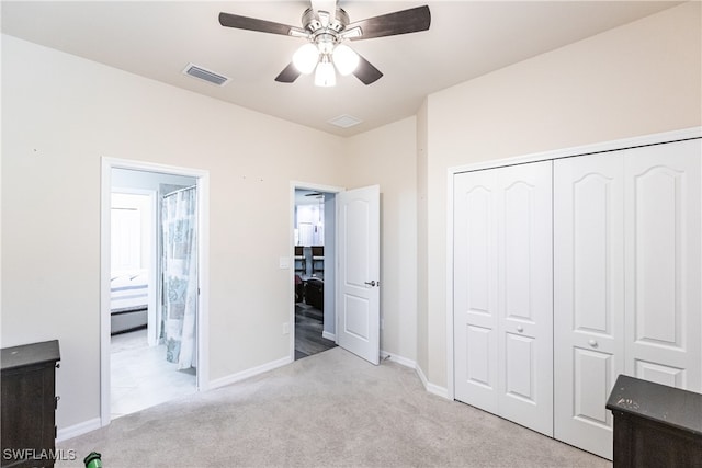 unfurnished bedroom featuring light carpet, ensuite bathroom, ceiling fan, and a closet